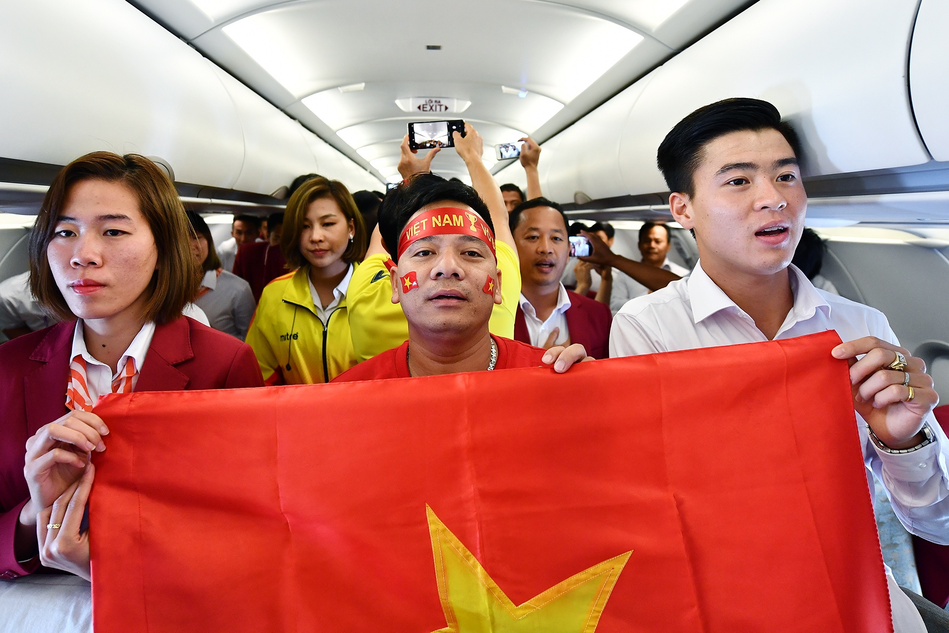 Cau thu doi Olympic Viet Nam hat Quoc ca tren may bay hinh anh