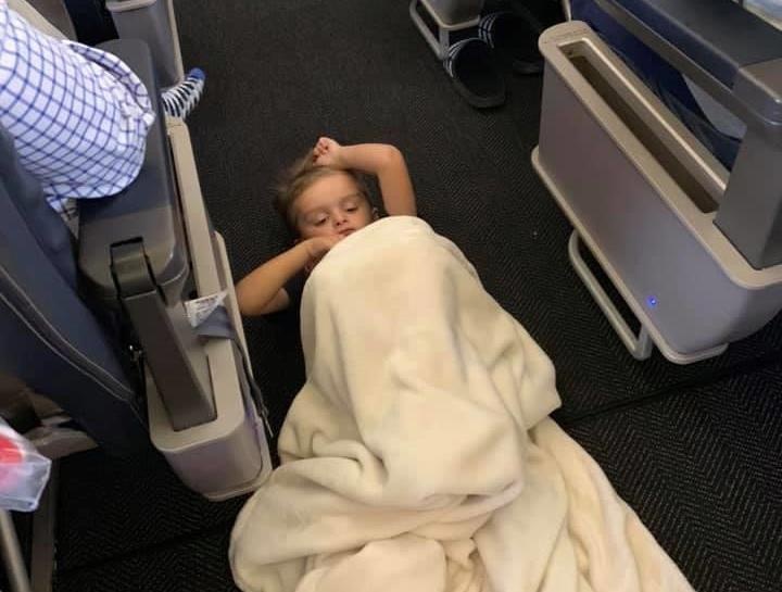 Cau be tu ky khong chiu ngoi tren may bay, tiep vien lay chan cho nam hinh anh