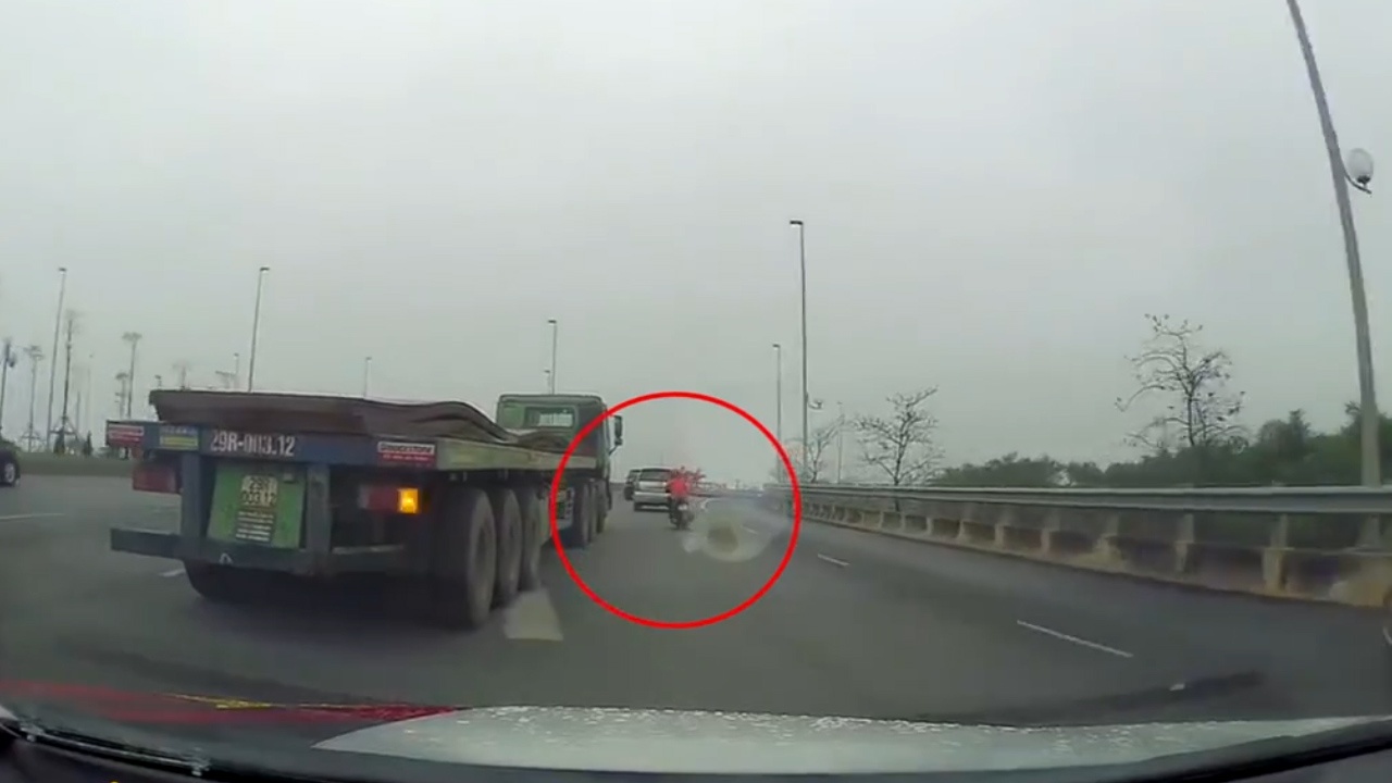 Nguoi phu nu chay xe tay ga tat dau container tren quoc lo hinh anh