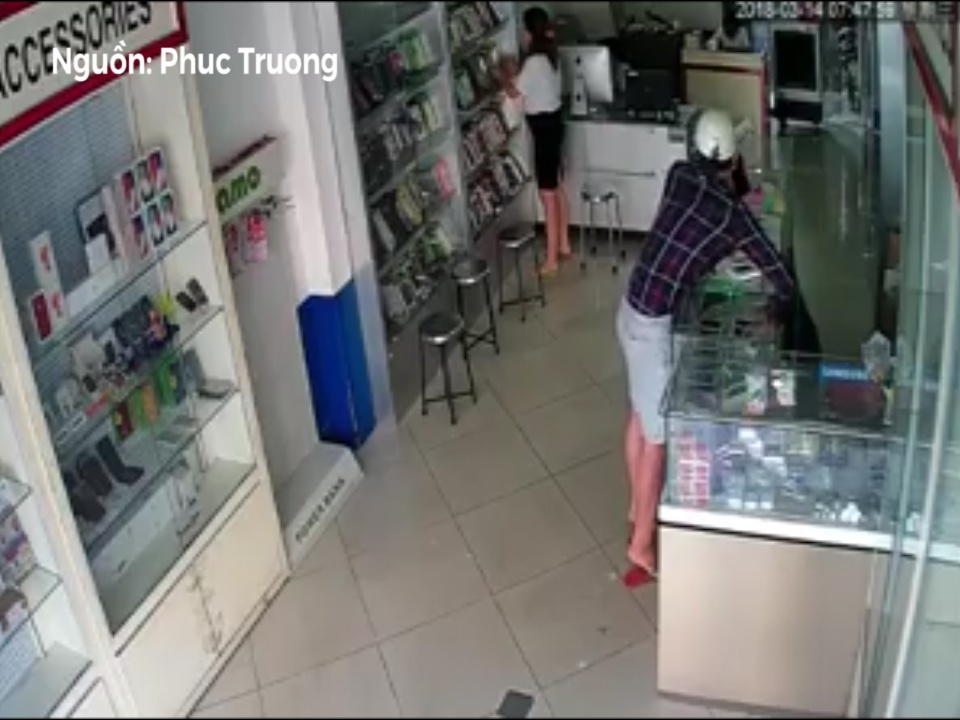 Thanh nien trom dien thoai khi chu cua hang dang dung ben canh hinh anh