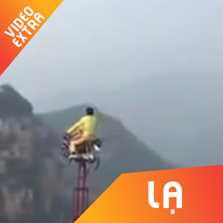 Nguoi dan ong lai xe may di tren soi day bang qua 2 day nui hinh anh