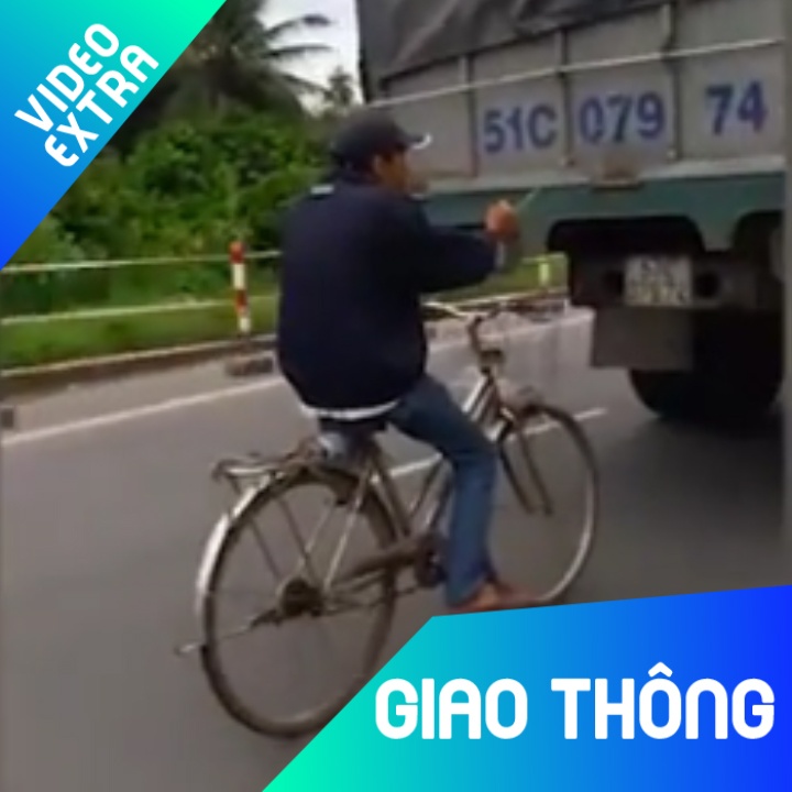 Nam thanh nien dap xe du theo xe tai len cau nguy hiem hinh anh