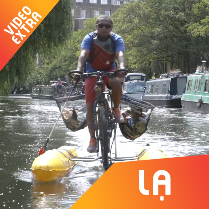 Nguoi dan ong dung xe dap 'nuoc' de nhat tui nhua tren con kenh hinh anh