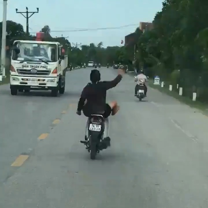 Thanh nien gac chan len xe, vua chay vua mua tay tren duong hinh anh