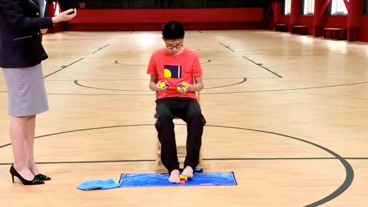 Cau be giai 3 khoi rubik bang hai tay hai chan nhanh nhat the gioi hinh anh