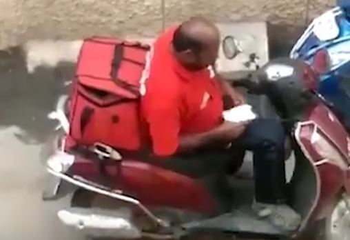 Nguoi giao hang An Do hon nhien an vung thuc an cua khach giua duong hinh anh