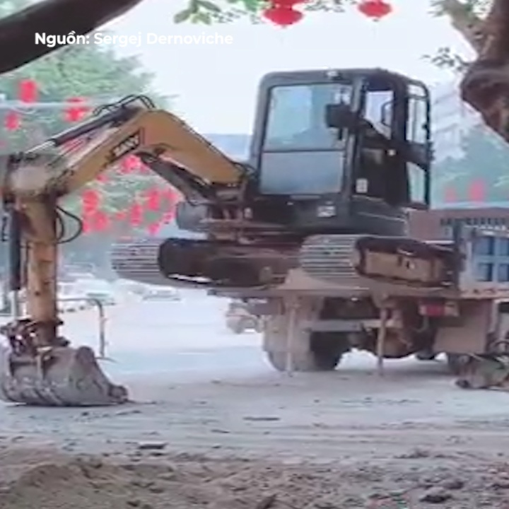 Tai xe dieu khien xe xuc dat len xe tai chi trong nhay mat hinh anh