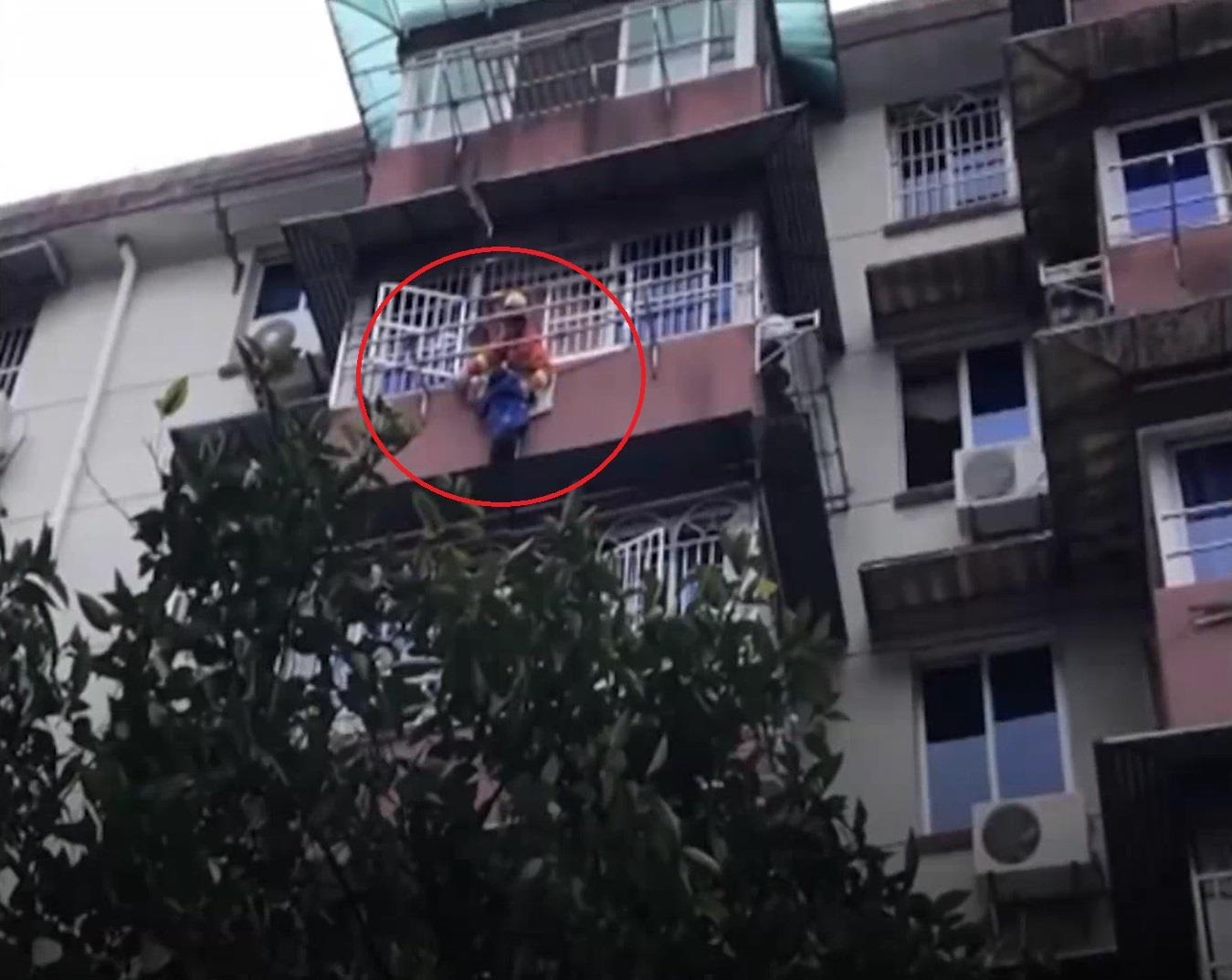 Be gai giu tay em trai lo lung ngoai ban cong suot 20 phut doi cuu ho hinh anh