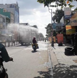 Chu tiem rua xe xit nuoc lam mat nguoi di duong giua trua nang hinh anh