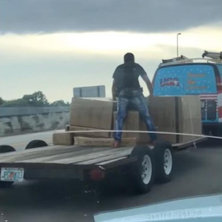 Nguoi dan ong vo tu dung tren ro mooc khi xe dang di chuyen hinh anh