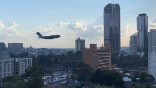 Canh may bay bay qua giua cac toa nha cao tang hinh anh