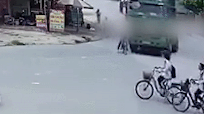 Hoc sinh di xe dap bi xe tai cuon vao gam, may man thoat chet hinh anh