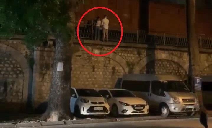 Doi nam nu bam hang rao xem tau chay hinh anh