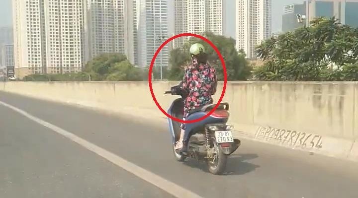 Nguoi phu nu vua lai xe may vua dung dien thoai tren cao toc hinh anh