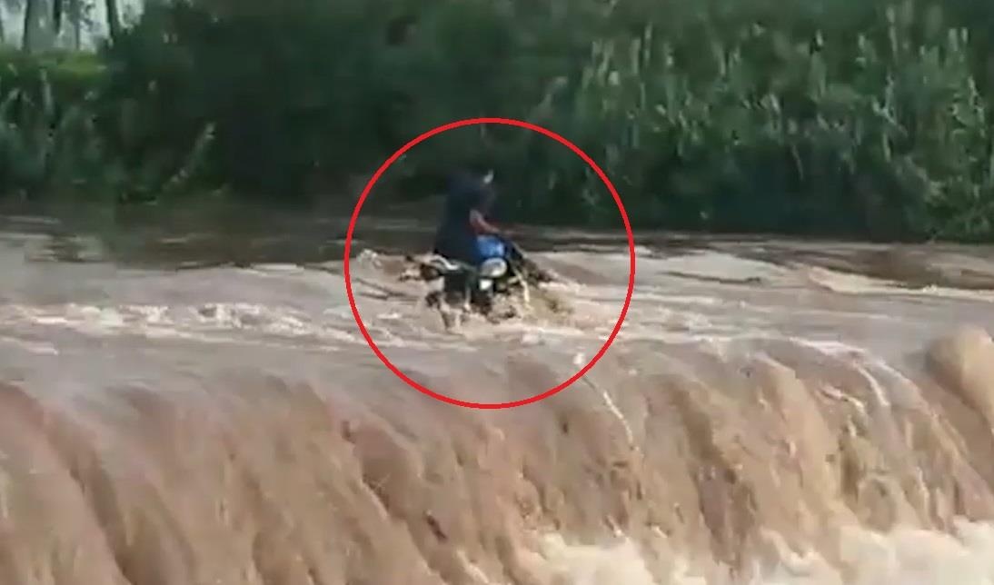 Xe may bi cuon troi vi co vuot qua dong nuoc lu hinh anh