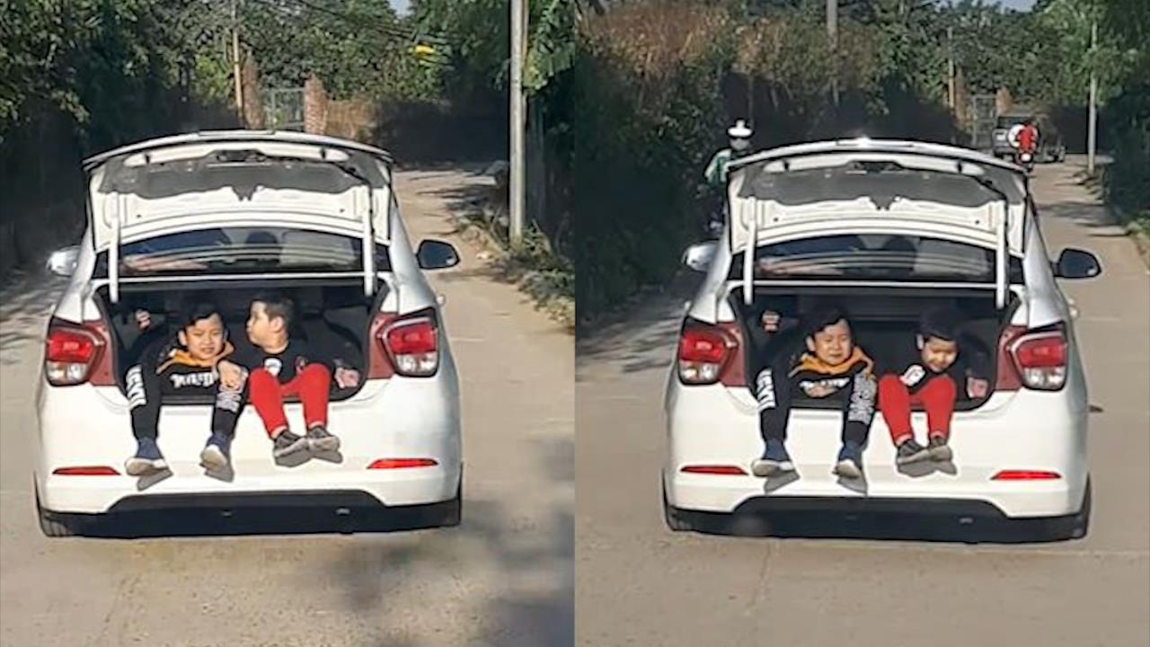 Oto cho 2 be trai ngoi trong cop xe chay tren duong hinh anh