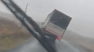 Xe tai chay trong mua bi lat nghieng do gio lon hinh anh