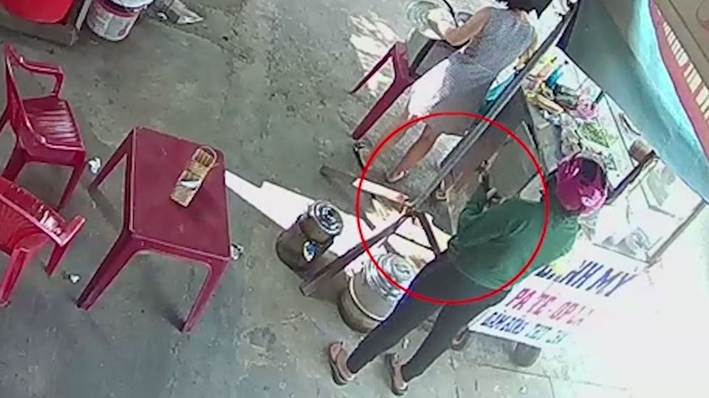 Nguoi phu nu trom dien thoai khi mua banh mi hinh anh