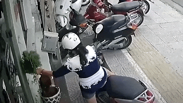 Nguoi phu nu gia vo nghe dien thoai, lay trom cay truoc cua hang hinh anh