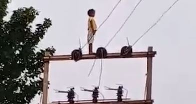 Cau be 5 tuoi treo len cot dien cao the de xem xe lua o An Do hinh anh