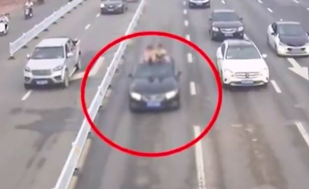 Hai dua tre ngoi tren noc oto chay tren duong hinh anh