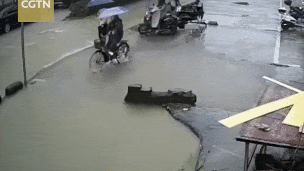 Co gai di xe dap lao xuong ho nuoc sau o giua pho tai Trung Quoc hinh anh