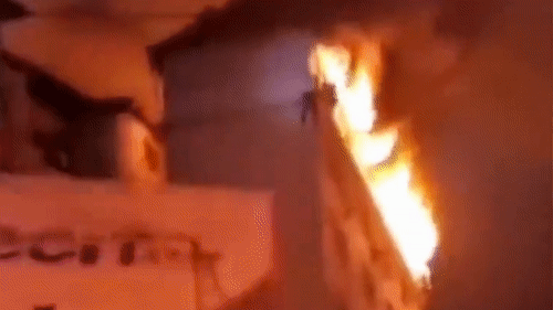 Nguoi dan ong treo theo ong nuoc de thoat khoi dam chay hinh anh