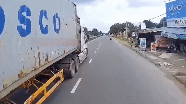 Nguoi dan ong lao ra duong nam truoc dau xe container hinh anh