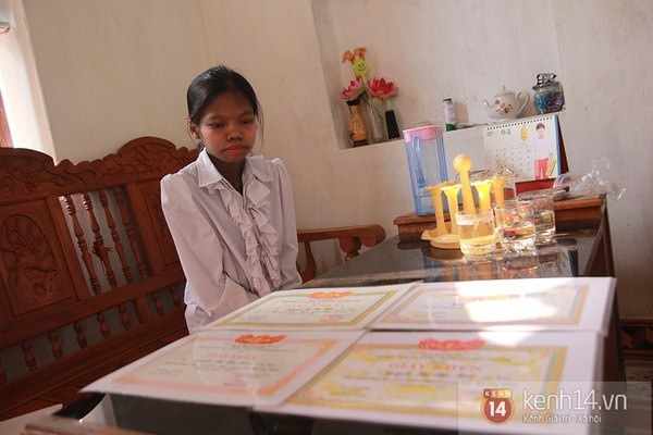 Hoài bên tập giấy khen mà mẹ em lưu giữ trong nhà.
