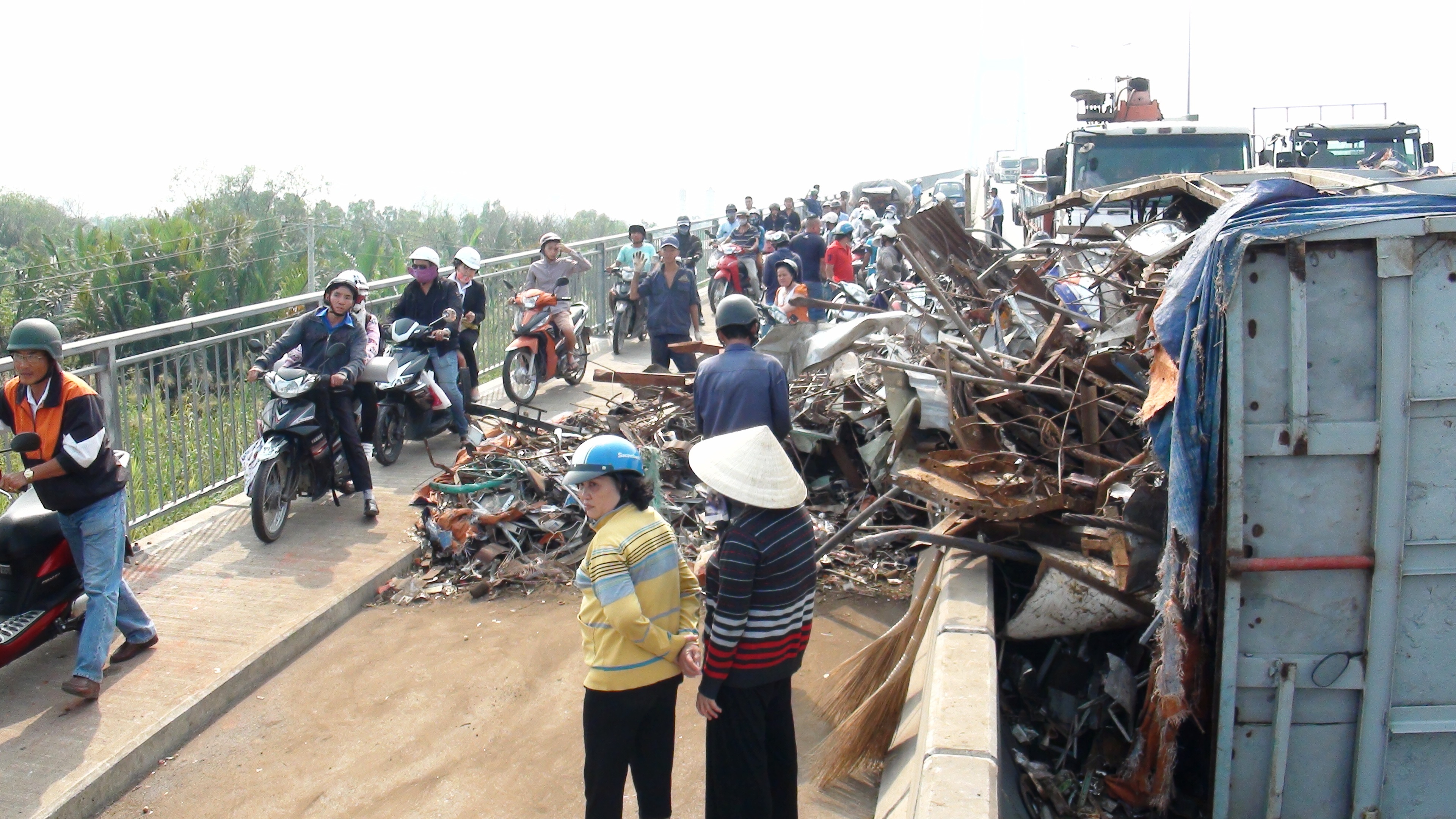 Xe tai lat tren cau, nguoi dan giup tai xe thu don phe lieu hinh anh