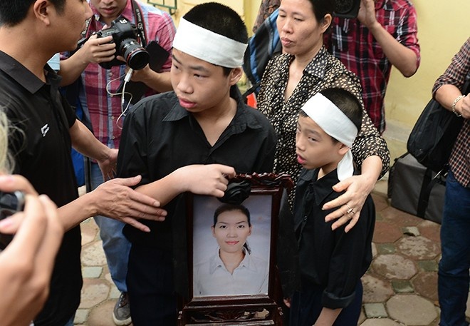 Hai người con trai của chị Huyền ôm di ảnh mẹ đến dự phiên tòa ngày 14/4.