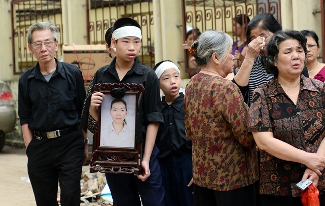 Nguyễn Hữu Hoàng (con lớn chị Huyền) học lớp 8 cùng em trai mang di ảnh mẹ đến phiên tòa Thấy cảnh hai cháu nhỏ đeo khăn tang và cầm di ảnh, nhiều người không cầm được nước mắt. Ảnh: Tuấn Mark.