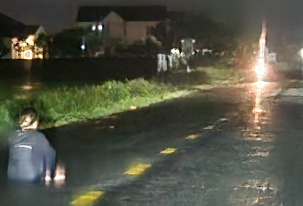 Nguoi phu nu ngoi giua duong trong dem mua hinh anh