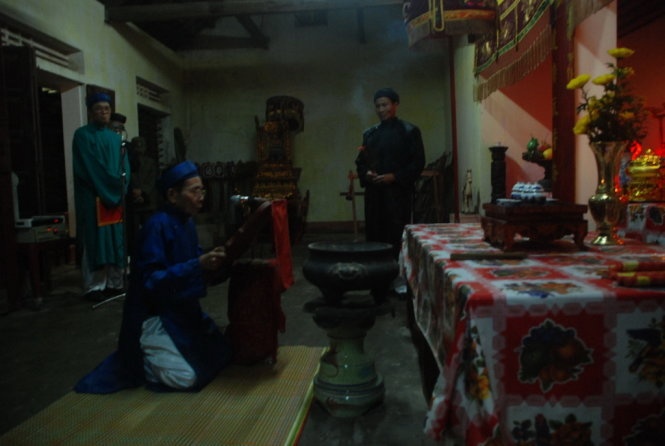 Ông Nguyễn Ngọc Liên, một bô lão trong làng Cảnh Dương thực hiện nghi lễ xin thần hoàng làng cho phép được rước lửa từ đình tổ ra sân đình - Ảnh: Quốc Nam