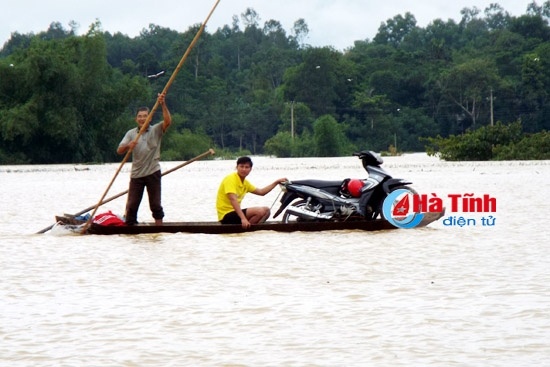 Đi lại khó khăn buộc người dân phải dùng thuyền chở xe máy ra quốc lộ 8A. Ảnh: Báo Hà Tĩn