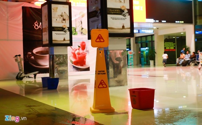 Tại những điểm dột trong nhà ga quốc nội, nhân viên sân bay phải đặt bảng cảnh báo trơn trượt. Ảnh: Hải An.