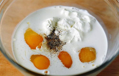 Trộn đều trứng với kem chua, half and half cream, muối và hạt tiêu, đánh đều cho hỗn hợp hòa quyện. Thịt xông khói cho vào chảo áp chảo chín vàng, cắt miếng nhỏ.