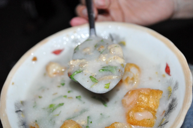 Cháo nóng hổi, lẫn cẫn thịt trai băm xào hành, bỏ thêm chút rau dăm rồi ăn kèm với quẩy giòn. Món cháo bình dân này xóm chợ, con phố nào cũng bán. 