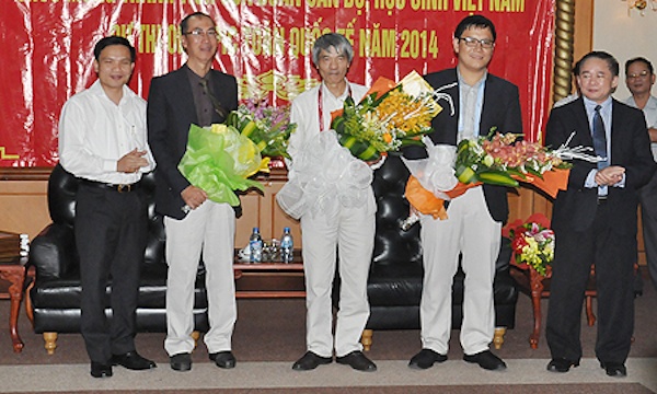 Thứ trưởng Bộ GD-ĐT Bùi Văn Ga (ngoài cùng bên phải) và Cục trưởng Cục Khảo thí&Kiểm định chất lượng, Bộ GD-ĐT Mai Văn Trinh (ngoài cùng bên trái) chúc mừng các thầy cô trong đoàn đưa thí sinh dự thi IM) 2014 trở về tại sân bay Nội Bài trưa 14/7.