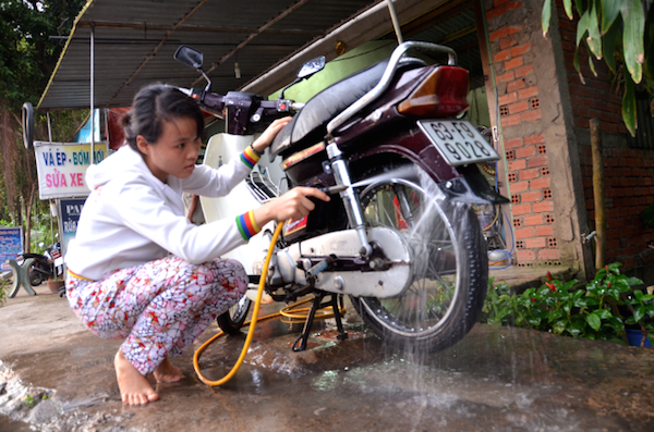 Tranh thủ ngày chủ nhật về thăm nhà, Trinh giúp cha rửa xe cho khách.
