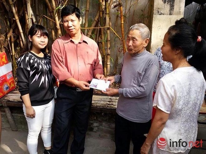 Một phụ huynh đi cùng trao phần quà cho người dân xóm chạy thận trên đường Lê Thanh Nghị.