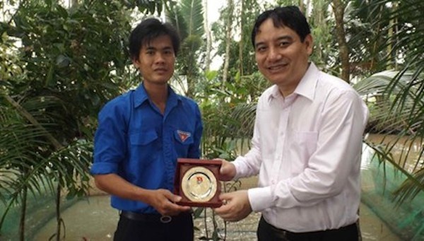 Anh Nguyễn Đắc Vinh tặng biểu trưng cho anh Khoa tại khu nuôi ếch.