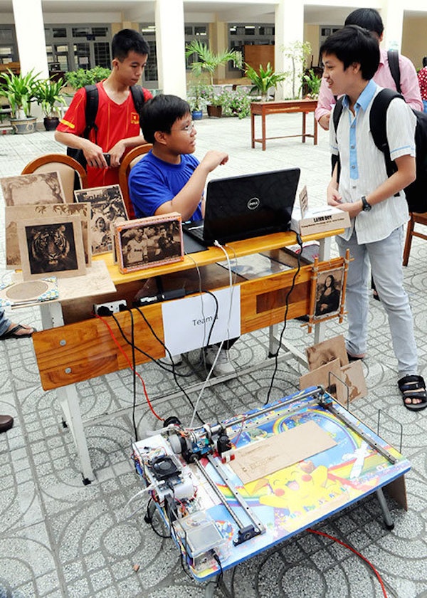 Nguyễn Dương Kim Hảo (ngồi) trò chuyện với các bạn học sinh về chiếc máy khắc laser của mình.