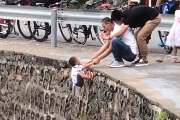 Nguoi dan ong TQ bi chi trich vi giu dua tre tren vach da de chup anh hinh anh