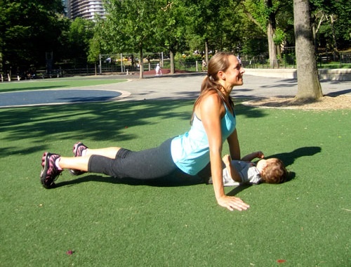 Động tác 2: Nằm úp bụng, giữ cho hông trên mặt đất khi bạn nâng thân lên, duỗi cơ bụng. Em bé nằm trên mặt đất, đối mặt với bạn. Sau đó bạn cúi xuống hôn bé rồi quay lại vị trí cũ. Lặp lại nhiều lần.