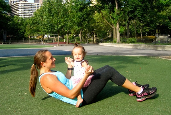 Động tác 9: Nằm ngửa, đầu gối cong 90 độ. Đặt bé ngồi trên bụng và nắm tay bé. Cố gắng dùng sức nâng người dậy, co cơ bụng, tiến lại gần rồi hôn em bé. Sau đó, trở lại vị trí ban đầu và lặp lại.