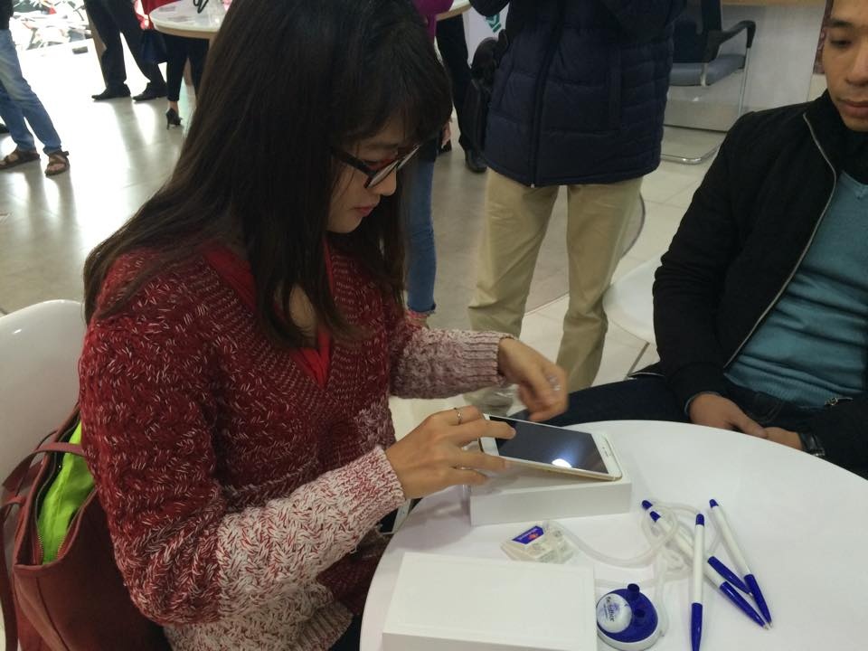 Chị Ánh tiến hành mở máy ngay tại cửa hàng. Vị khách đầu tiên này cho biết, chị rất thích thiết kế mới với màn hình to của iPhone 6 Plus ngay từ khi máy mới ra, nhưng đợi mua hàng chính hãng để được an tâm với chế độ bảo hành. Ảnh: Thành Duy.