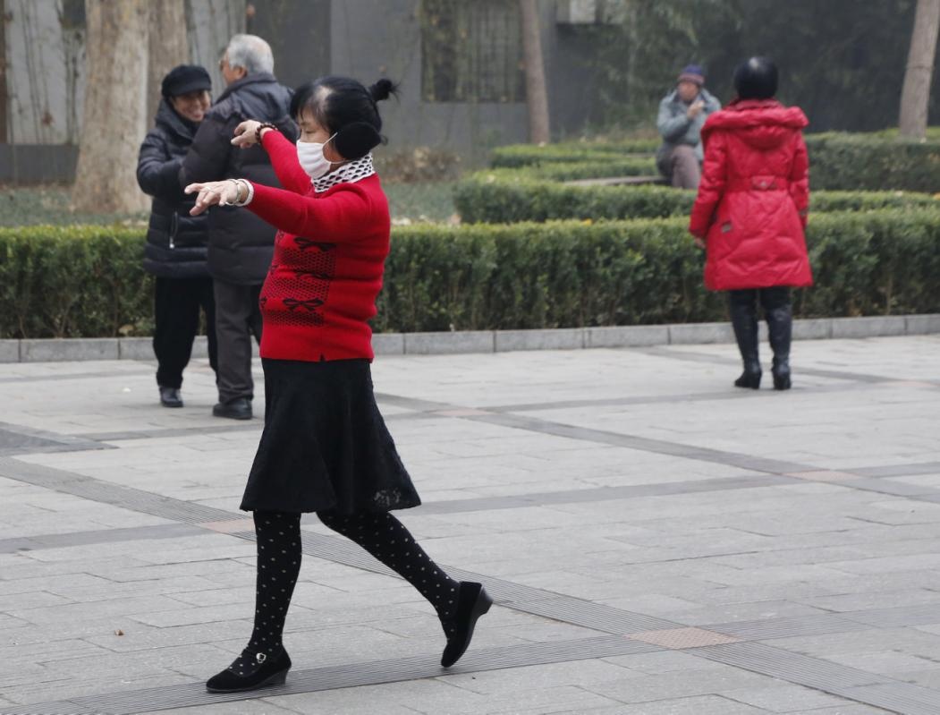 Một phụ nữ đeo khẩu trang khi tập khiêu vũ trong một công viên ở thành phố Bắc Kinh hôm 8/12. Ảnh: Reuters