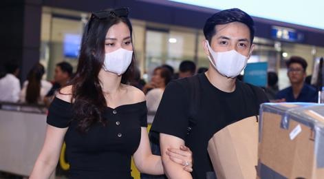 Dong Nhi - Ong Cao Thang mac ao doi, nam tay nhau o san bay hinh anh