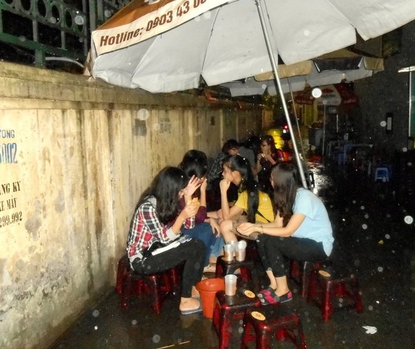 Bất chấp mưa gió, nhiều thực khách vẫn tìm đến quán ăn vỉa hè của Đức, co cụm dưới những chiếc ô để thưởng thức món thịt xiên nướng.